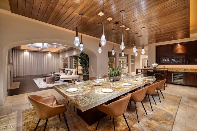 dining area with wet bar, wine cooler, wood ceiling, and arched walkways