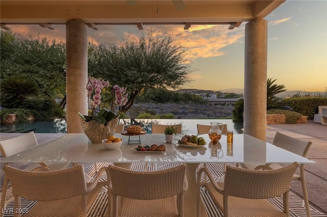 patio terrace at dusk featuring outdoor dining space and a ceiling fan