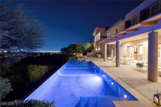 pool at twilight with a patio and ceiling fan