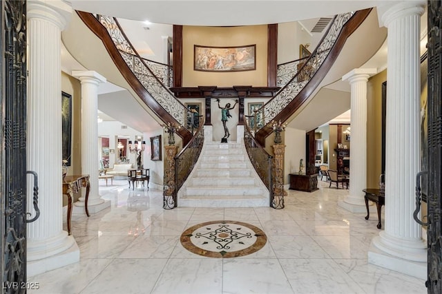 entryway featuring a towering ceiling and decorative columns