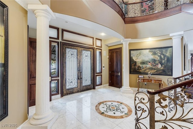 foyer with decorative columns, a towering ceiling, and french doors