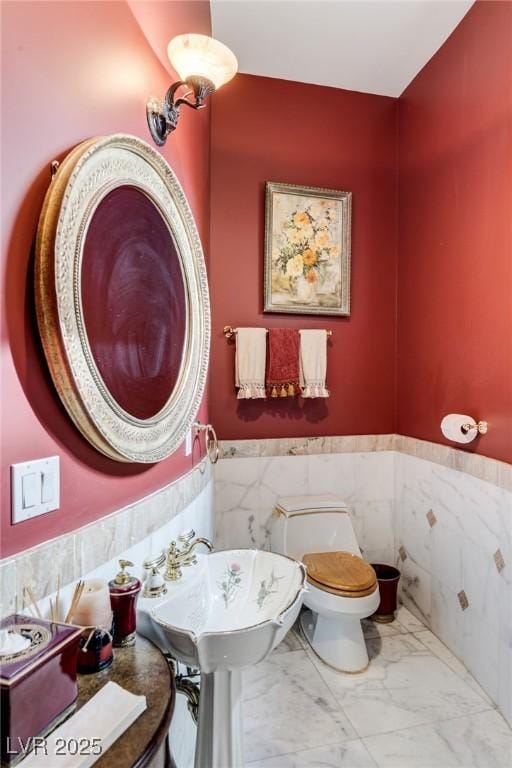 bathroom with toilet and tile walls