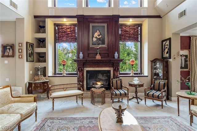 sitting room featuring a high end fireplace and a high ceiling