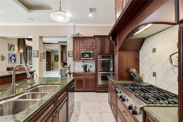 kitchen featuring sink, appliances with stainless steel finishes, dark stone countertops, hanging light fixtures, and decorative backsplash