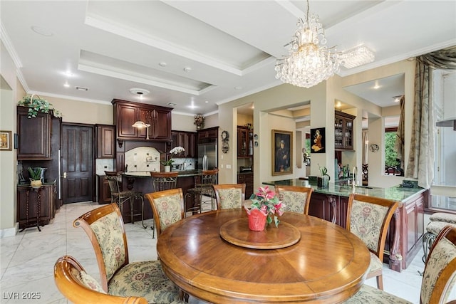 dining space with ornamental molding, a tray ceiling, and a notable chandelier