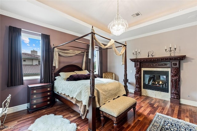 bedroom with crown molding, a notable chandelier, dark hardwood / wood-style floors, and a raised ceiling