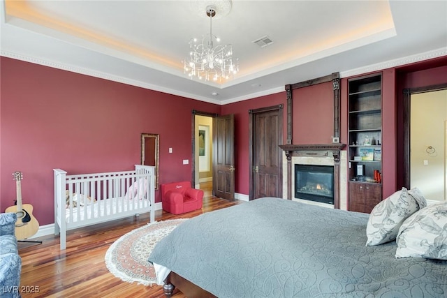 bedroom featuring an inviting chandelier, hardwood / wood-style floors, and a raised ceiling