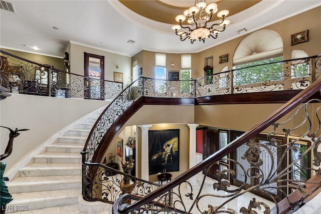 stairs featuring a high ceiling, ornamental molding, a chandelier, and a tray ceiling