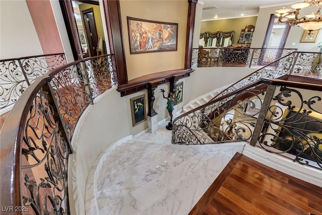 staircase with crown molding and a notable chandelier