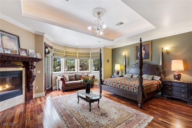 bedroom with dark hardwood / wood-style flooring, a raised ceiling, and an inviting chandelier