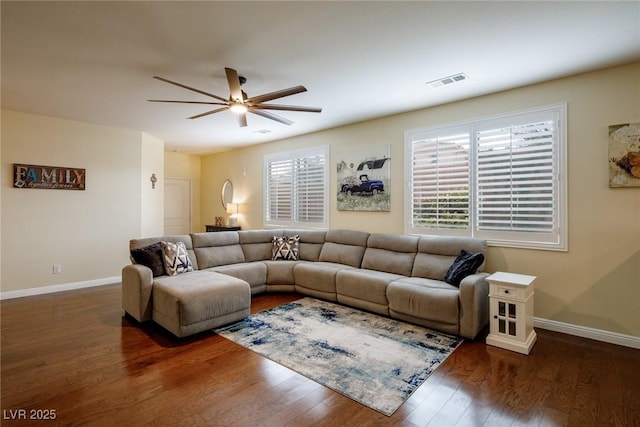 living room featuring dark wood-type flooring, ceiling fan, and a wealth of natural light