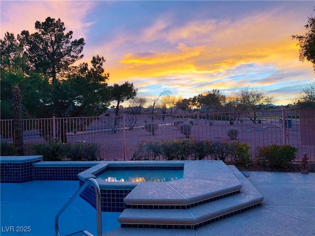 pool at dusk with an in ground hot tub