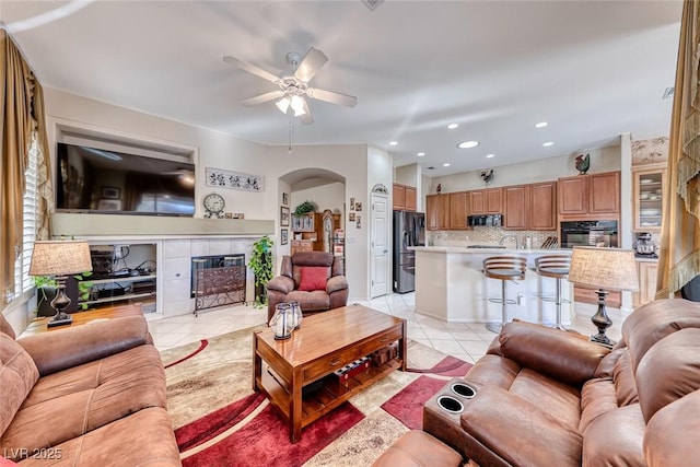 living room featuring light tile patterned flooring, ceiling fan, and a fireplace