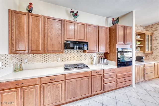 kitchen featuring backsplash, light tile patterned floors, and black appliances