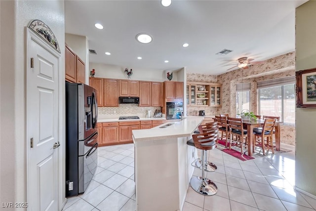 kitchen featuring sink, a kitchen breakfast bar, a center island, light tile patterned floors, and stainless steel appliances