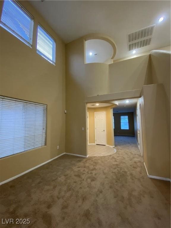 unfurnished living room featuring a towering ceiling and carpet flooring