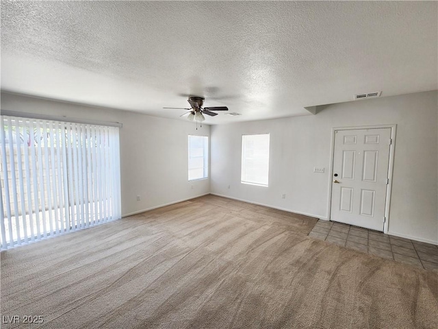 carpeted spare room with a textured ceiling and ceiling fan