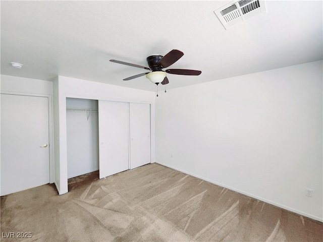 unfurnished bedroom featuring ceiling fan, a closet, and light carpet