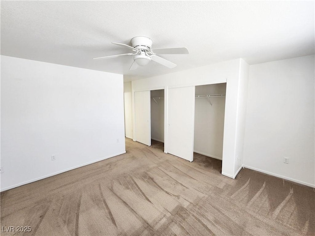 unfurnished bedroom with multiple closets, light carpet, and ceiling fan