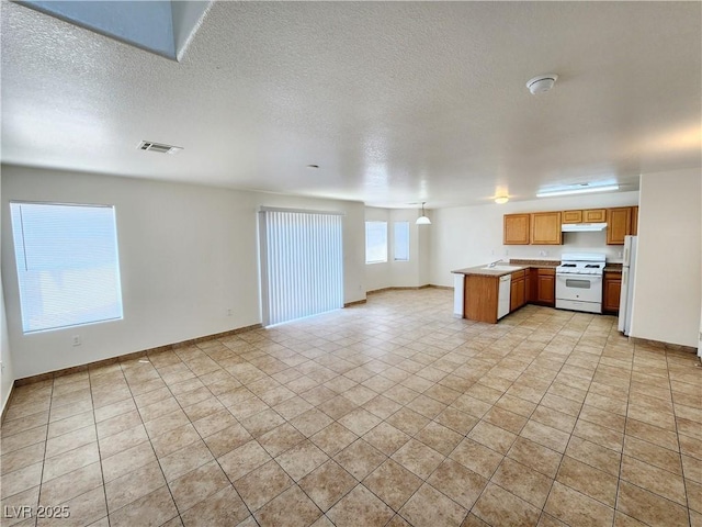 kitchen with a textured ceiling, white appliances, and kitchen peninsula