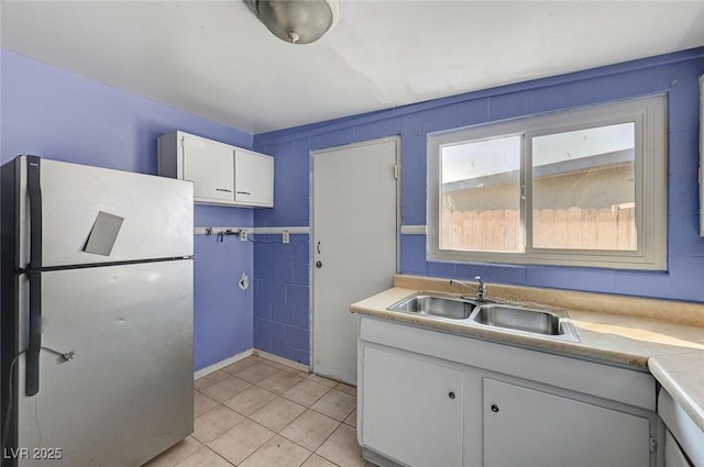 kitchen with fridge, sink, light tile patterned floors, and white cabinets