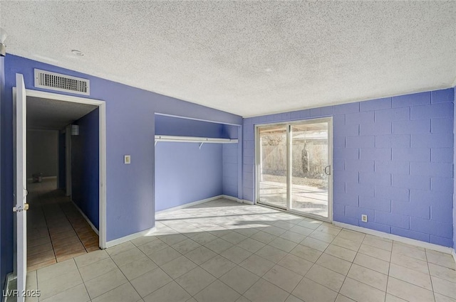 unfurnished bedroom with access to exterior, a closet, a textured ceiling, and light tile patterned flooring