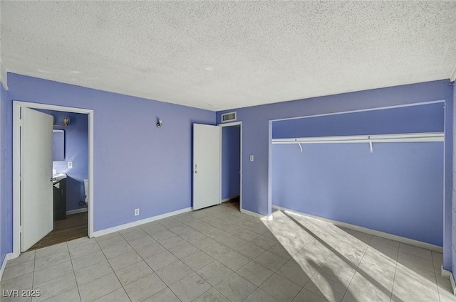 unfurnished bedroom with a closet, a textured ceiling, and light tile patterned floors