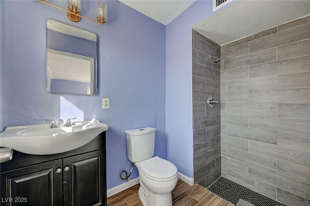 bathroom with vanity, a tile shower, and toilet