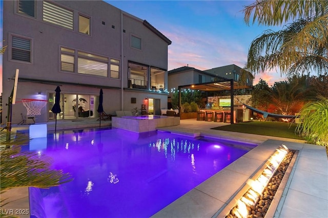 pool at dusk featuring a patio and exterior bar