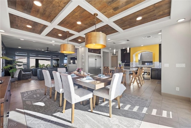 tiled dining space with coffered ceiling, beamed ceiling, wooden ceiling, and ceiling fan