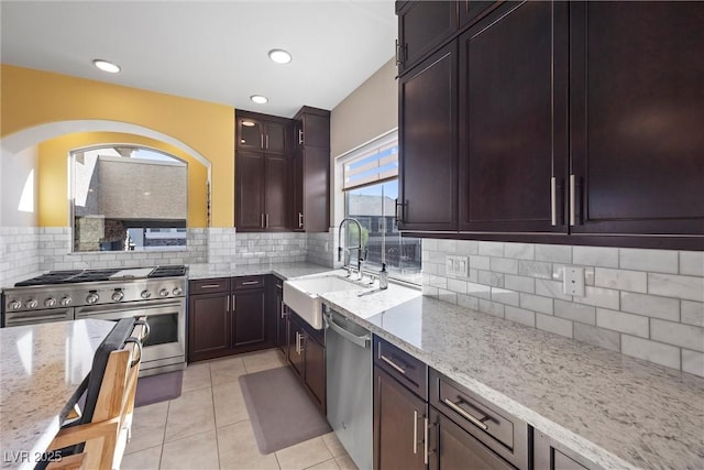 kitchen featuring appliances with stainless steel finishes, sink, light tile patterned floors, and light stone counters