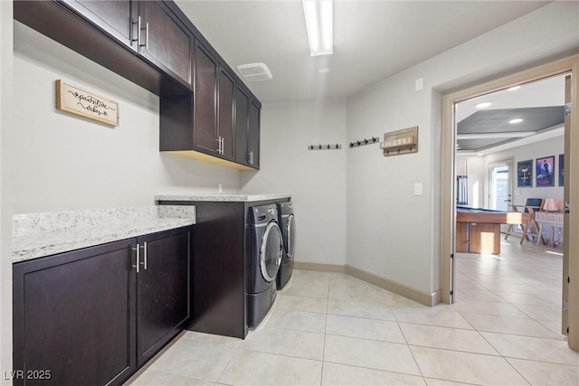 clothes washing area with light tile patterned flooring, cabinets, and washer and clothes dryer