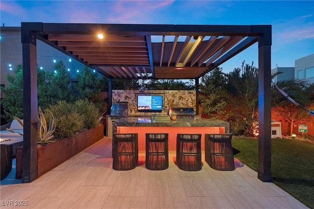 patio terrace at dusk with area for grilling, a grill, a pergola, and exterior bar