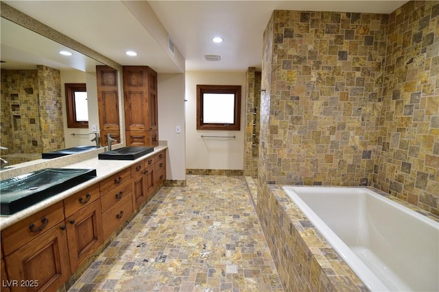 bathroom featuring vanity and tiled bath