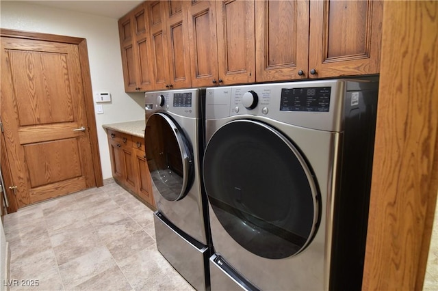 laundry area with separate washer and dryer and cabinets