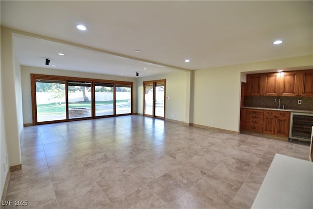 unfurnished living room with beverage cooler and indoor wet bar