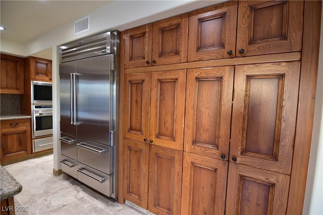 kitchen featuring built in appliances and light stone countertops