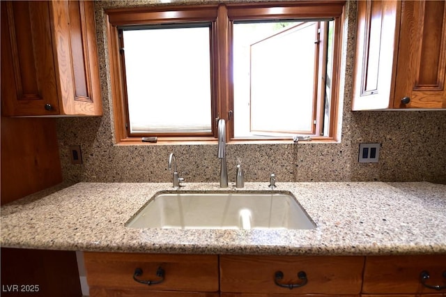 kitchen with light stone counters, sink, and plenty of natural light