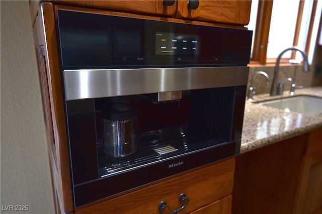 interior space featuring light stone counters, oven, and sink