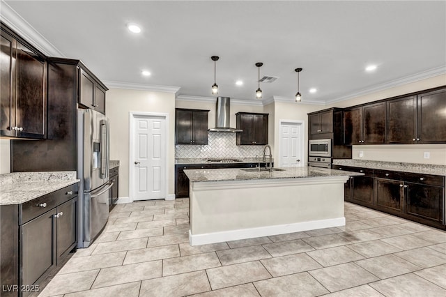 kitchen featuring sink, hanging light fixtures, a kitchen island with sink, stainless steel appliances, and wall chimney range hood