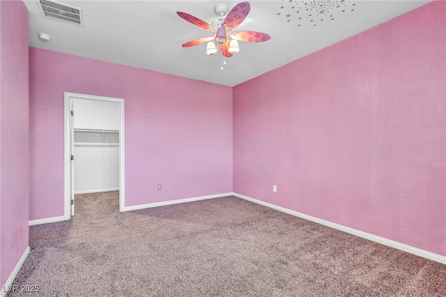 unfurnished bedroom featuring a spacious closet, a closet, ceiling fan, and carpet