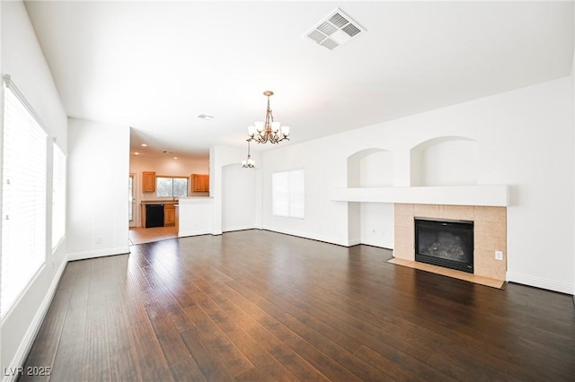 unfurnished living room featuring dark hardwood / wood-style flooring, a notable chandelier, and a fireplace