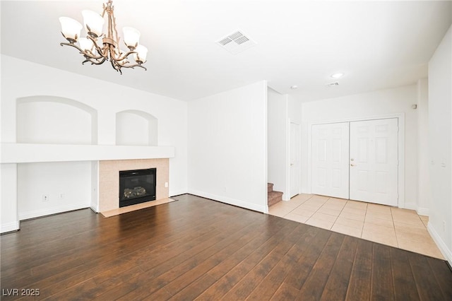 unfurnished living room with an inviting chandelier, a fireplace, and light wood-type flooring