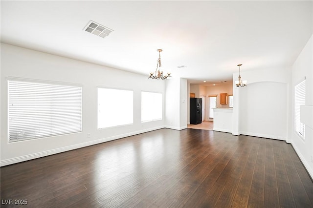 unfurnished living room with an inviting chandelier and dark wood-type flooring