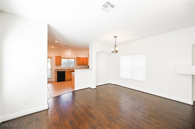 unfurnished living room featuring sink, a chandelier, and light hardwood / wood-style floors