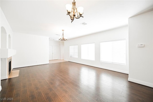 unfurnished living room with an inviting chandelier and dark hardwood / wood-style floors