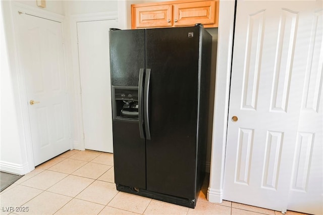 kitchen featuring light brown cabinetry, light tile patterned floors, and black refrigerator with ice dispenser