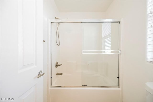 bathroom with bath / shower combo with glass door and toilet