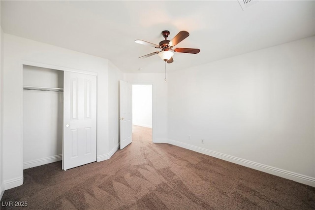 unfurnished bedroom with ceiling fan, dark carpet, and a closet