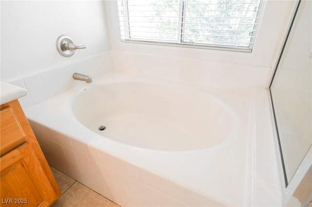 bathroom featuring vanity, tiled tub, tile patterned flooring, and a wealth of natural light